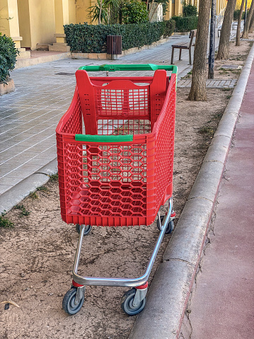 Close-up view of red shopping cart abandoned in the sidewalk in the city of Valencia, Spain