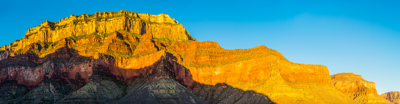 The vibrant desert walls of the South Rim illuminated by the warm light of sunrise from the remote Tonto Trail deep in the Grand Canyon National Park, Arizona, USA.