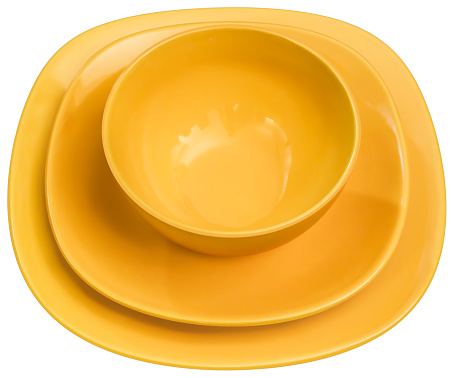 Studio shot of three pieces dining set, consisted of Yellow Ceramic Soup Bowl with two matching Plates, isolated on white background, side view.