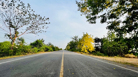 Beautiful country road with beautiful sky background and Cassia fistula tree