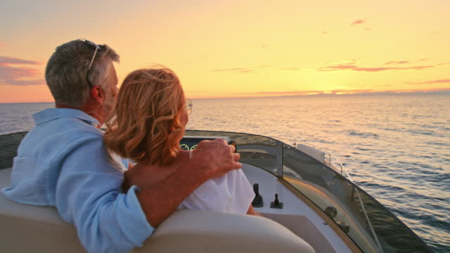 SLO MO Senior couple enjoying the view of the sunset from the bridge of the yacht