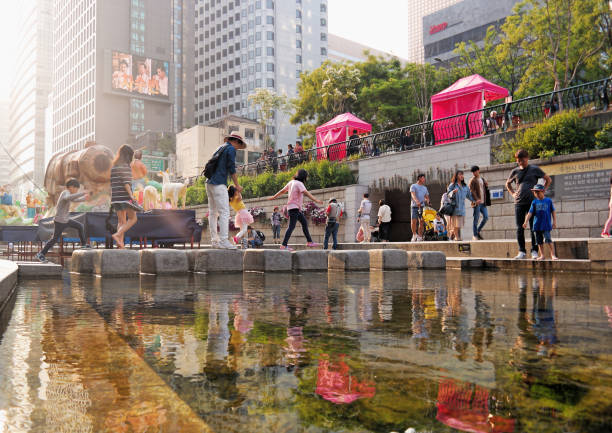 Seoul, South Korea,  Scenic reflection view of people on the Cheonggye Stream (Cheonggyecheon) at sunset Seoul, South Korea - May 2019:  Scenic reflection view of people on the Cheonggye Stream (Cheonggyecheon) at sunset berk stock pictures, royalty-free photos & images