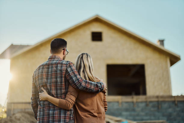 Looking at developing house! Rear view of an embraced couple looking at built structure from outside. Copy space. home ownership stock pictures, royalty-free photos & images