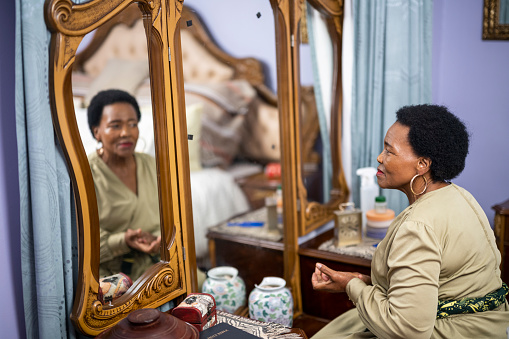 Senior woman getting ready for church sitting at dressing table in bedroom