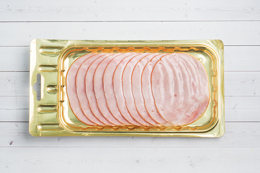 Pork ham in thin slices in a vacuum package on the table. Meat sliced carbonate in a package for long-term storage