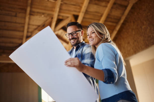 istock Happy couple reading housing plans at construction site. 1484800569