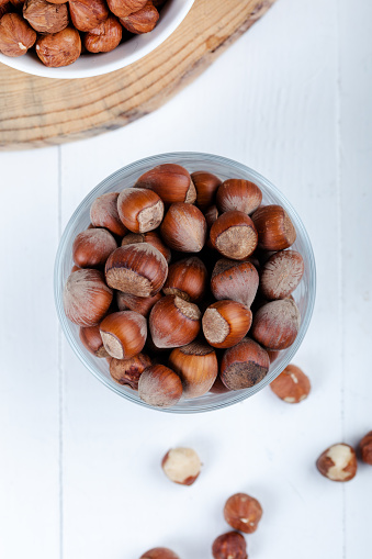 Shelled hazelnuts in a bowl on a white wooden background. Top view.