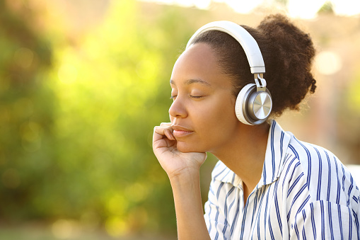Relaxed black woman listening music resting in a park