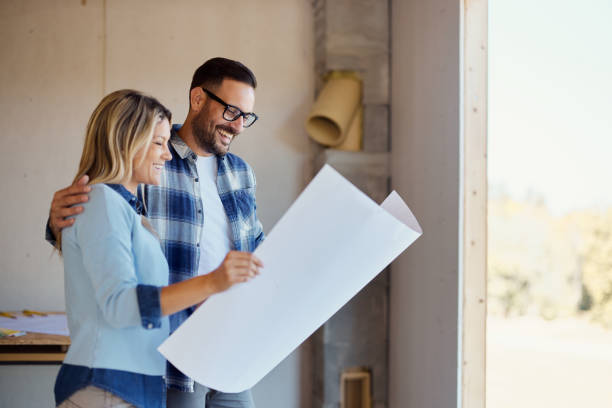 istock Embraced couple reading blueprints of their developing house. 1484801257