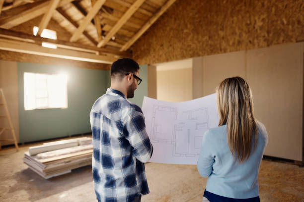 istock Back view of a couple reading housing plans at construction site. 1484801463
