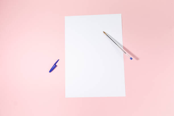 istock empty white paper sheet and a pen on pink background. Mockup 1484804693