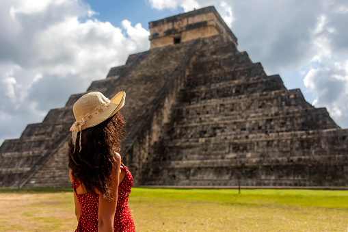 Woman with the Mayan ruins of Chichen Itza in the context of Yucatan and Caribbean Mexico. Civilization concept, Mayan culture and vacations.