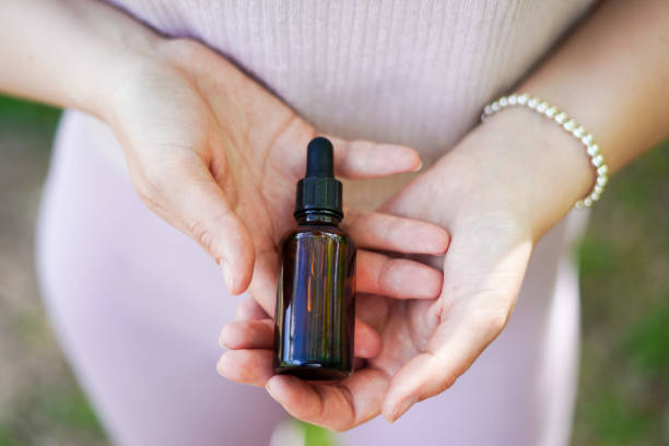 Femme tenant une bouteille en verre avec de l'huile cosmétique de spa. Thérapie en salon, produits naturels de soins du corps écologique