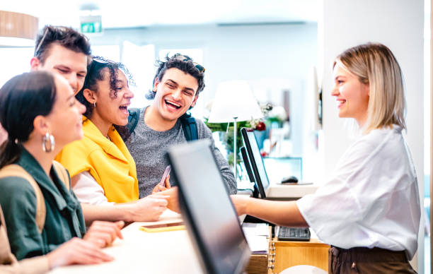 Young diverse friends having fun time at luxury hotel reception on check in time - Travel life style concept with happy people waiting at guesthouse desk on fancy vacation - Bright vivid filter stock photo
