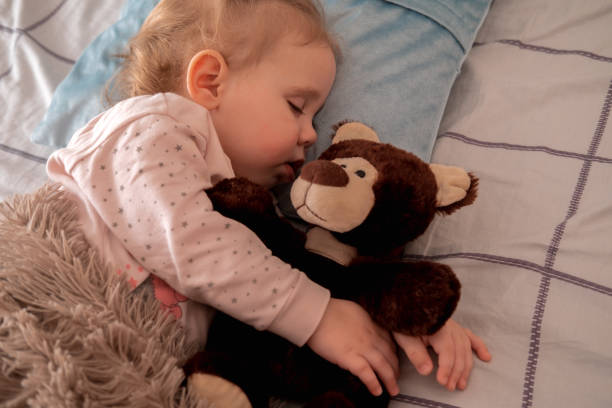 istock Cute little girl sleeping and hugging brown teddy bear. Top view. 1484813481