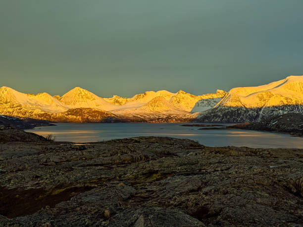 snow-capped mountains lit by the evening sun at a fjord in Norway stock photo