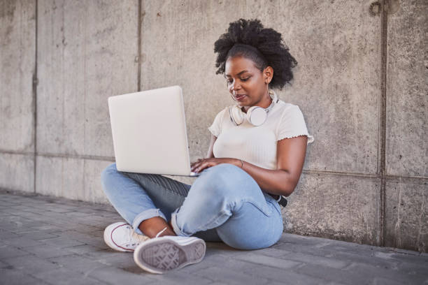 istock Young woman sitting with laptop typing lean against concrete wall 1484818836