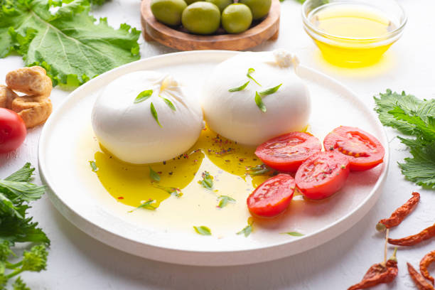 apulian cuisine, ingredients, south italy, burrata, cheese, mozzarella, bufala, olive oil, taralli, tomatoes, turnip tops, cima di rapa, pepperoncini, culinary traditions, puglia, bari - mozzarella cheese italy tomato imagens e fotografias de stock