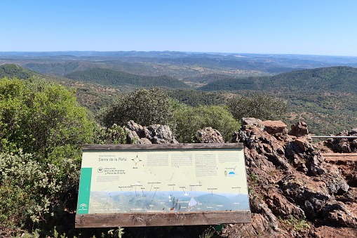 Pena de Arias Montano, Alajar, Huelva, Spain, April 23, 2023: View of the mountains with information sign from the viewpoint of the Peña de Arias Montano, Alajar, Huelva, Spain