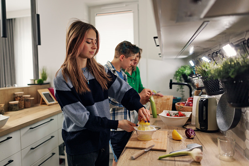 Generation Z  teenage kids making vegetable salad. The girl is making lemon juice and the boy is peeling a cucumber
Shot with Canon R5