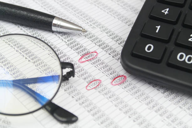 istock Black glasses with pen and calculator on papers with financial data and red marks. 1484825523