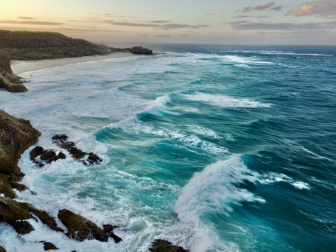 Aerial drone view of rough Seas and rips on North Stradbroke Island in Queensland Australia - drone aerial view of Point Lookout showing rip and current. Waves crashing onto rocks. Sunset over stradbroke island.