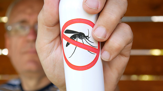 A man holding anti mosquito spray in his hand close-up