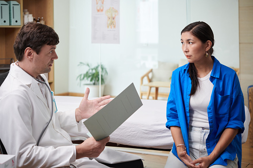 Worried woman listening to doctor explaining her diagnosis anf recovery process