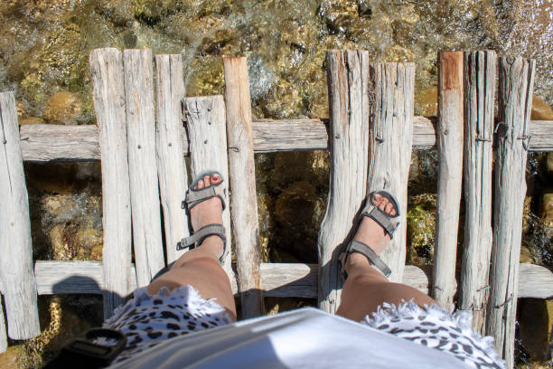 Woman's legs on an old wooden bridge through the river top view