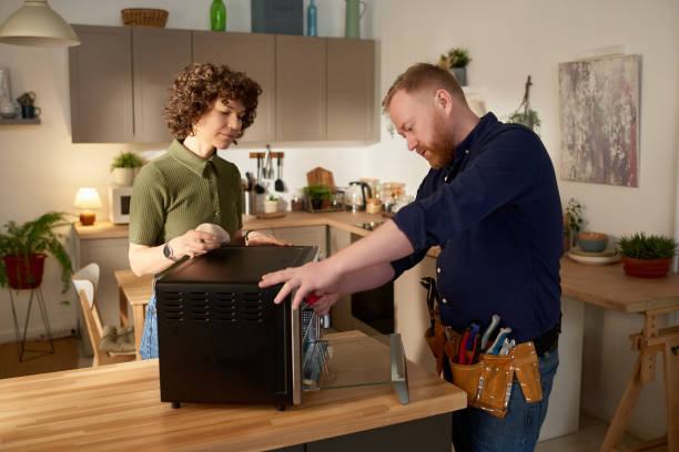 Repairman fixing microwave oven at home stock photo