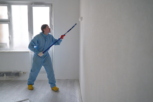 Man paints the ceiling with a roller. Concept of home makeover and renovation