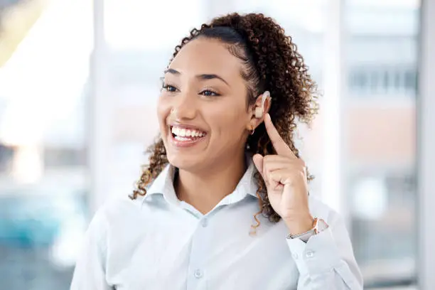 Photo of Happy, deaf and black woman with cochlear implant in office for communication, translation and speech on blurred background. Disability, hearing and female employee for sign language, hand or gesture