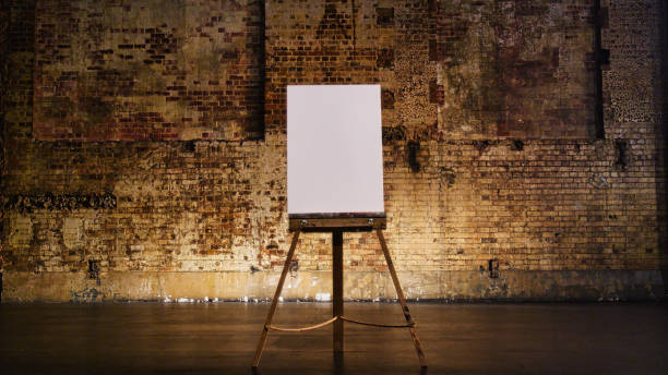 istock A blank canvas sitting on an easel in front of a rustic brick wall on a theatre stage 1484838343