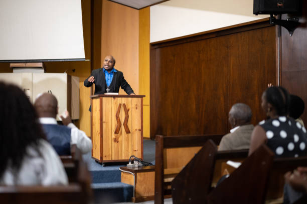 Over shoulder view pastor preaching from pulpit Multi-generation family and congregation enjoying church service black gospel church stock pictures, royalty-free photos & images