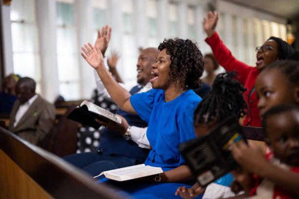 Amen! Woman raises her hand in agreement Multi-generation family and congregation enjoying church service black gospel church stock pictures, royalty-free photos & images