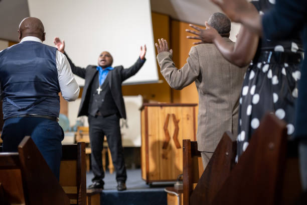 istock Pastor stand preaching with arms raised in front of congregation 1484840184