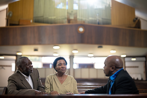 Pastor habla con pareja mayor en la iglesia dando apoyo photo