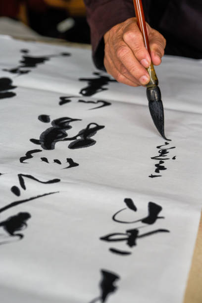 an old calligrapher is writing and creating calligraphy works. translation: it rains on the pond with light thunder outside liuwai, and the sound of r - inkstone imagens e fotografias de stock