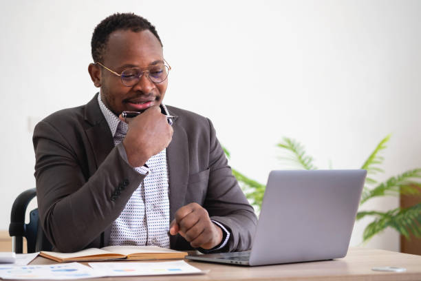 istock African American businessman analyzing laptop graph paperwork in office holding documents preparing portfolio analysis report Black male analyst doing paperwork in the workplace using the computer. 1484842079