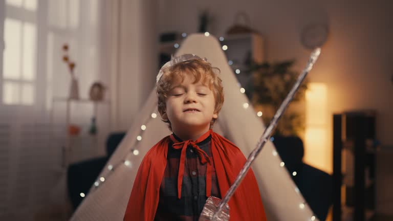 Portrait of little boy with diy crown and toy sword in front of a blanket fort