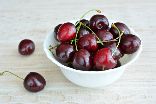 A bowl of cherries on a wooden table isolated, close-up