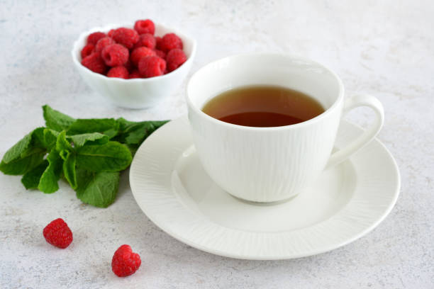 istock herbal tea in white cup on saucer with mint leaves and raspberry in bowl 1484842985