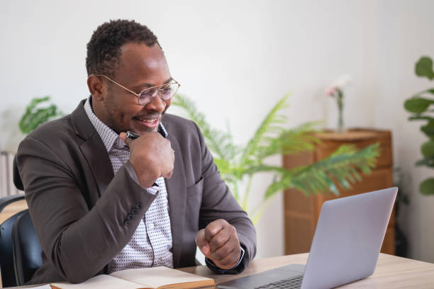istock African American businessman analyzing laptop graph paperwork in office holding documents preparing portfolio analysis report Black male analyst doing paperwork in the workplace using the computer. 1484843360
