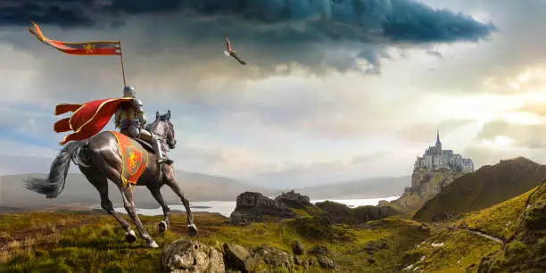 A medieval knight wearing full armour and helmet, holding a flag on a pole, sits on a horse riding on grassy coastal land over rocky hills towards a large distant castle on a rocky outcrop at dawn/dusk as a stormy cloud looms overhead. An eagle leads the way.
