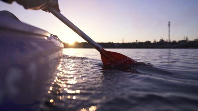 Oar paddles on calm water against the background of sunset rays, outdoor activities on a kayak, water sports