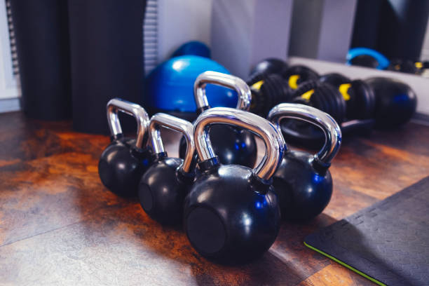 istock Five black kettlebells with different weights. Sports equipment in the gym. Adjustable dumbbells, gymnastic hemisphere, weighted ball and yoga mats on background. 1484853166