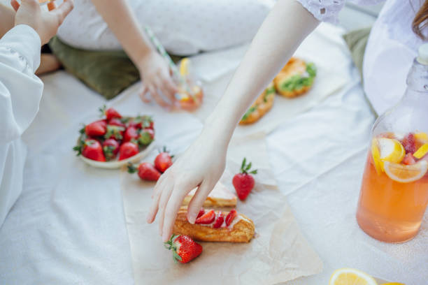 lanket with pillows and food on a wooden bridge. Bottle of strawberry and lemon smoothie Picnic on the bank of a river. Blanket with pillows and food on a wooden bridge. Bottle of strawberry and lemon smoothie, soda glasses with straws, herb croissants, sweet cakes and fresh strawberries tremoctopus gelatus stock pictures, royalty-free photos & images