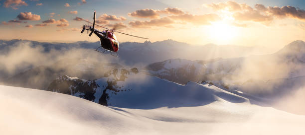 화려한 일몰 동안 록키 산맥 위로 날아가는 헬리콥터 - rescue helicopter mountain snow 뉴스 사진 이미지