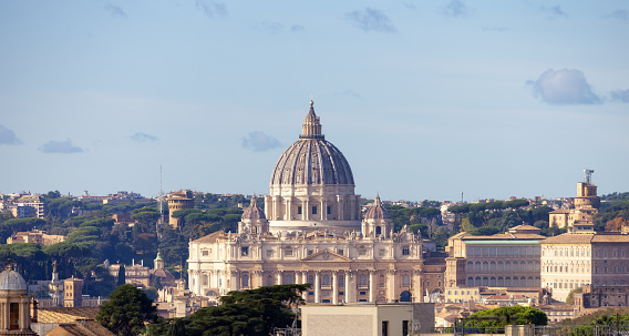 Vatican, January 01 -- A blanket of fog envelops the dome of St. Peter and the monumental statues on the facade of the Basilica and on Bernini's Colonnade (left). Characterized by giant columns and pilasters, the immense facade of San Pietro (118 meters wide and 48 high), was conceived by the architect Carlo Maderno to complete Michelangelo's previous project and built between 1608 and 1614. The Basilica of St. Peter's, in the Vatican, is the center of the Catholic religion, one of the most visited places in the world and in Rome for its immense artistic and architectural treasures. In 1980 the historic center of Rome was declared a World Heritage Site by Unesco. Super wide angle image in high definition format.