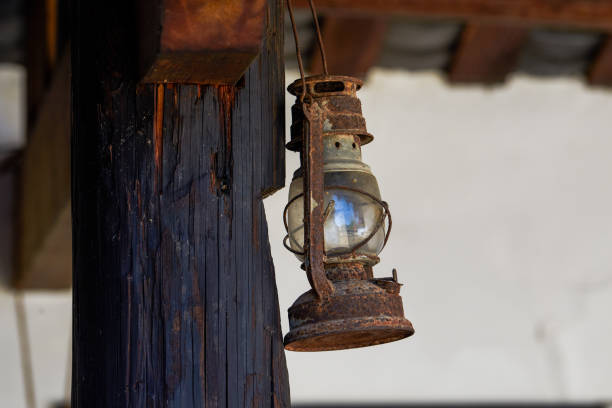 나무 말뚝에 매달려 있는 복고풍 등유 램프의 클로즈업 - lantern lamp hurricane old 뉴스 사진 이미지